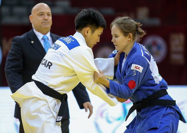 Nicolina Pernheim greppar motståndaren i en match på Grand Prix i Baku 2019. Båda står upp. I bakgrunden syns en domare.