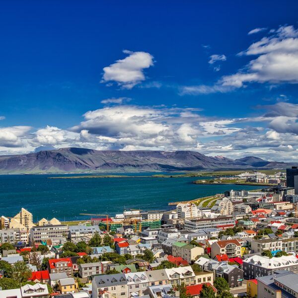 Bild över Reykjavik. Många hus i förgrunden, hav och berg i bakgrunden.