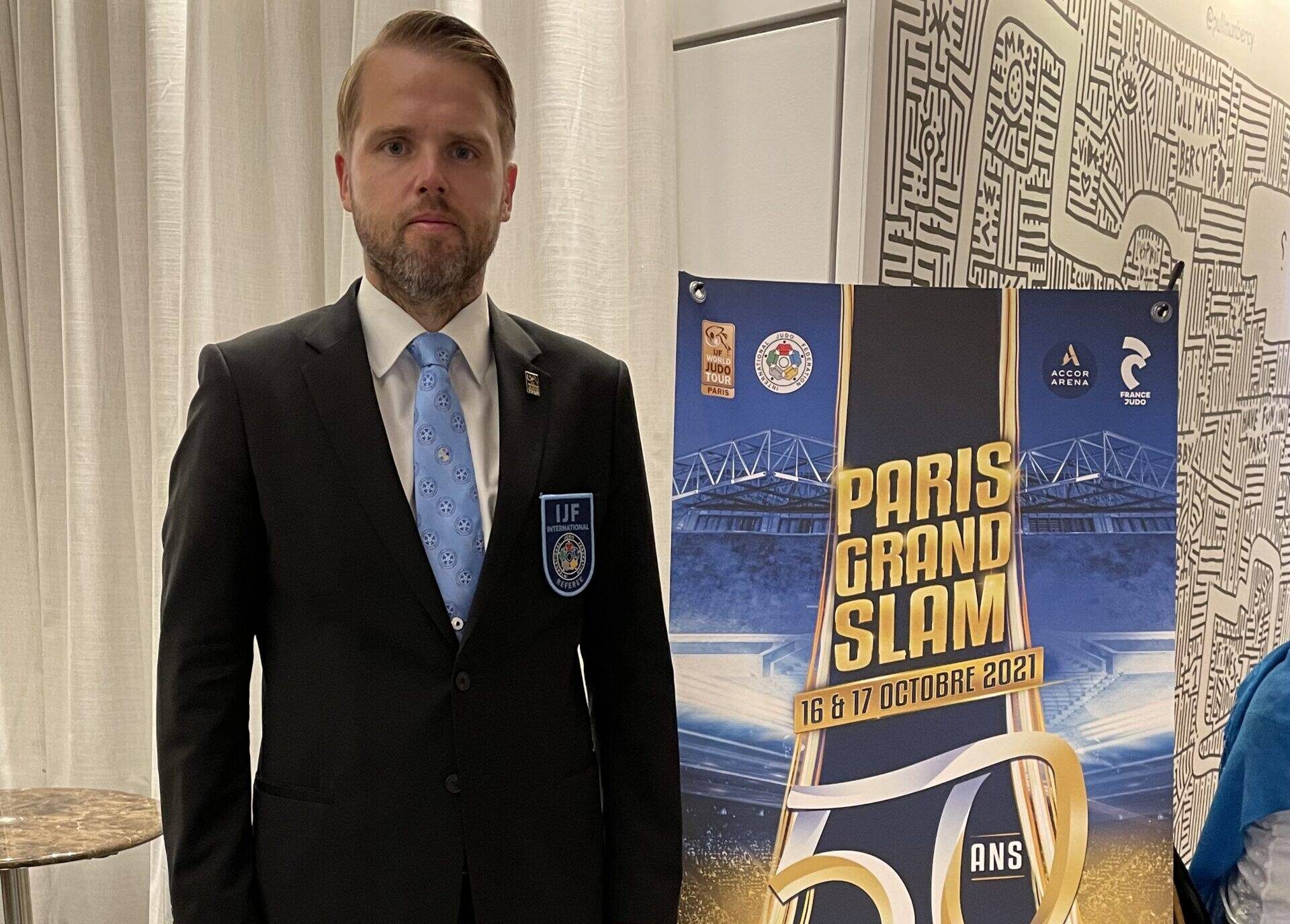 Björn Nyberg i svart kostym framför en roll-up för Paris Grand Slam.