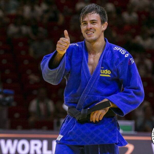 Tommy Macias i blå judodräkt ler och visar tummen upp.